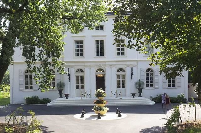 Photo de la façade extérieure d'un château et de son parc