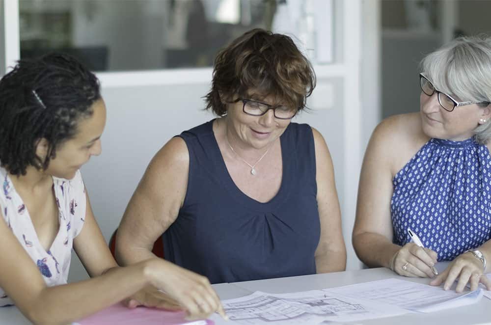 Photo de trois femmes qui travaillent sur un plan d'architecte