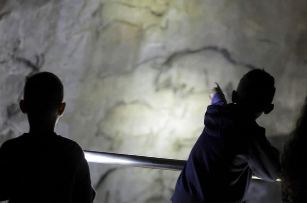 Deux enfants regardent des dessins préhistoriques